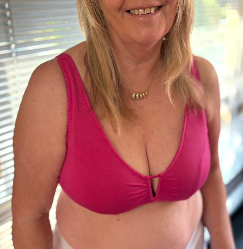 customer wearing Belle maternity bra in rosy, holding baby, opening the drop down cup