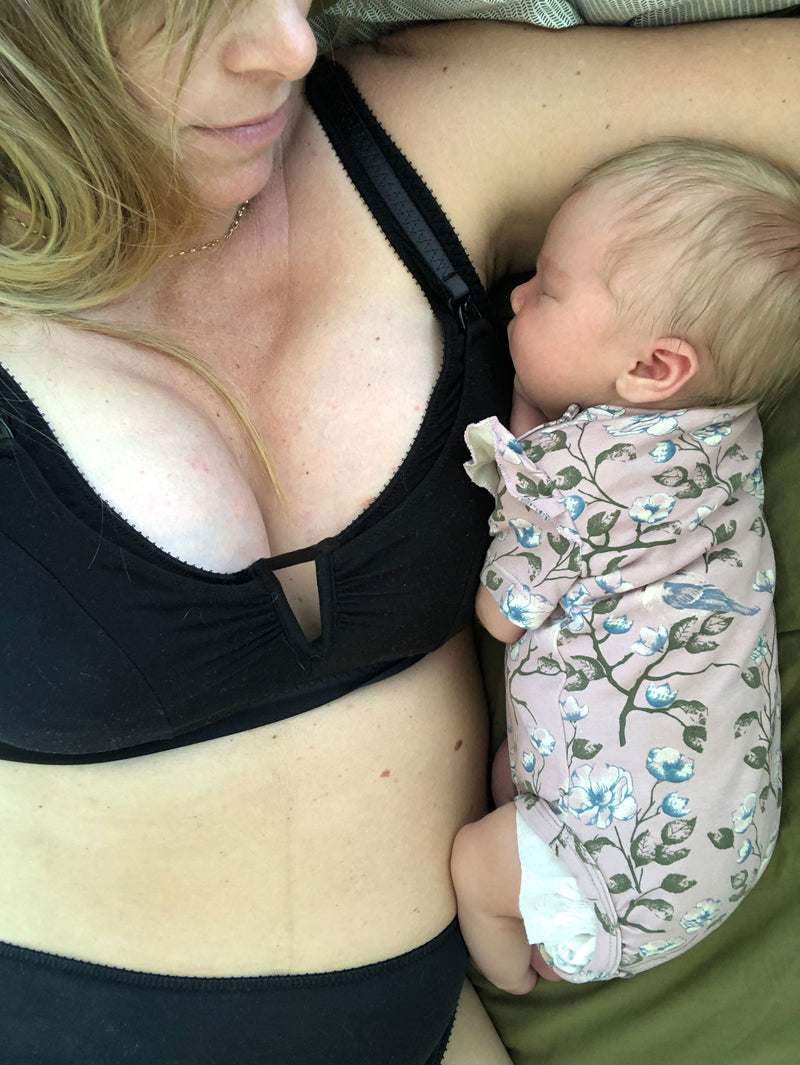 customer wearing belle maternity bra in shield, baby snuggling lying down