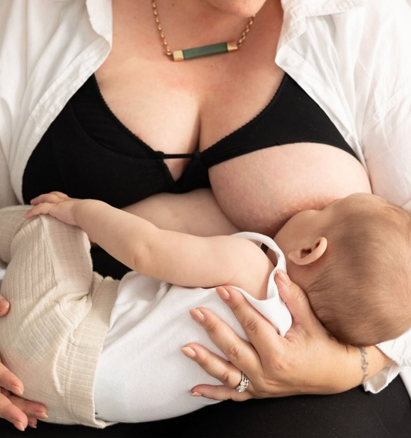customer wearing Belle maternity bra in shield black, holding baby, breastfeeding