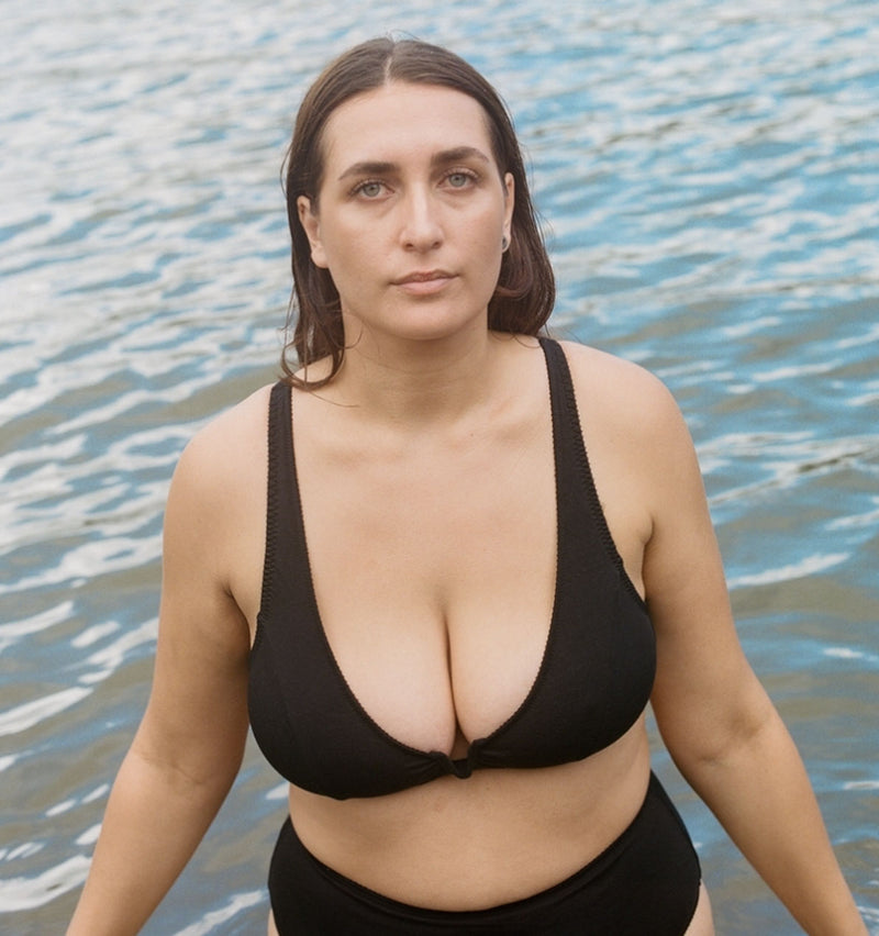 customer wearing Belle maternity bra in rosy, holding baby, opening the drop down cup